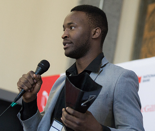 McGill student winning the Desautels Faculty of Management Dobson Cup prize and speaking into a micrcophone while holding a trophy