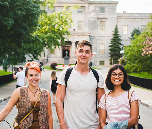 Three students standing on the pathway in front of the McCall MacBain building.