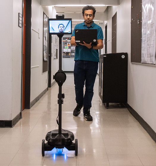 A person walking in a hallway with a computer