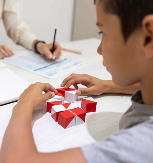 A child working on a puzzle with someone taking notes
