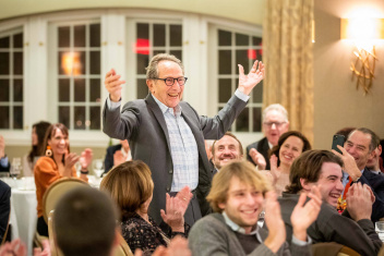 Person with hands raised in a room full of people