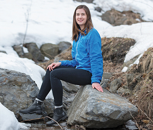 McGill alumna sitting on rocks with a snowy background