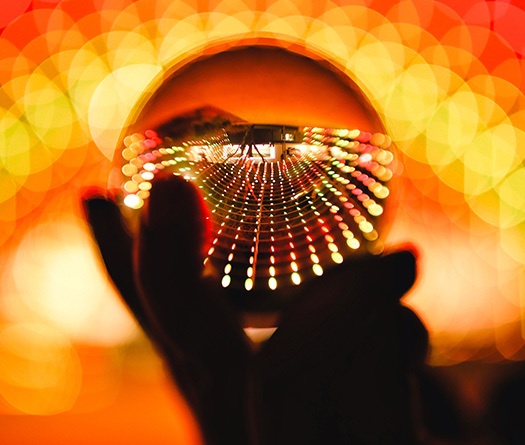A hand holding a crystal ball with lights in the background