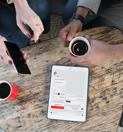 A group of people sitting at a table with coffee and a tablet