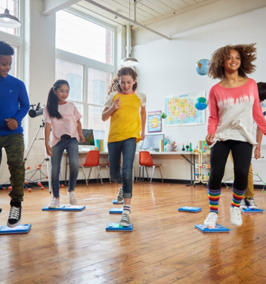 Four children in a classroom, jumping on programmable floor buttons