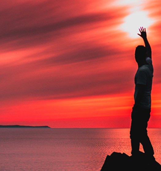 Person standing by ocean at sunset