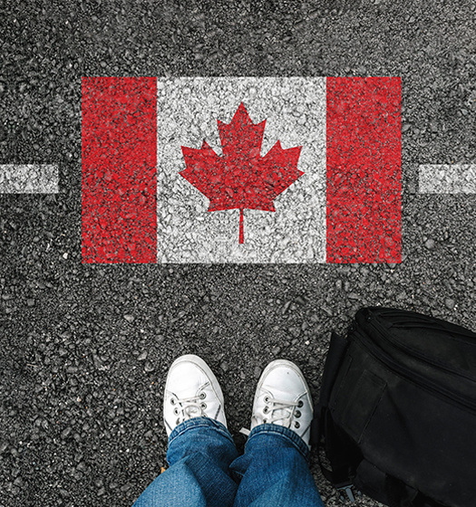 Feet facing the Canadian Flag on asphalt