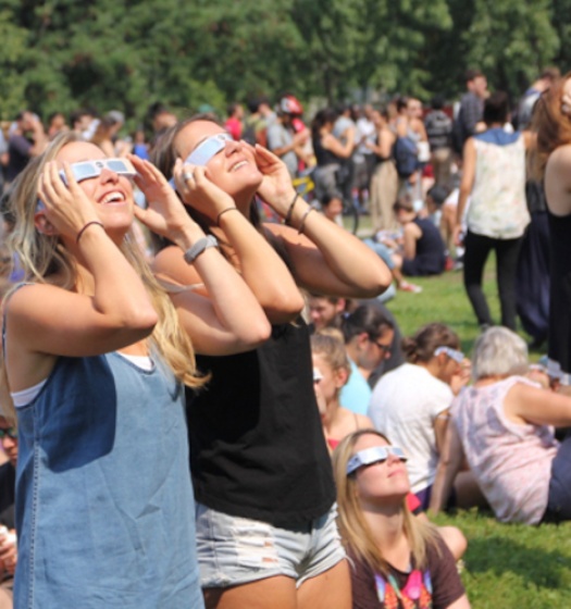A crowd looking up at the sky with eclipse glasses.