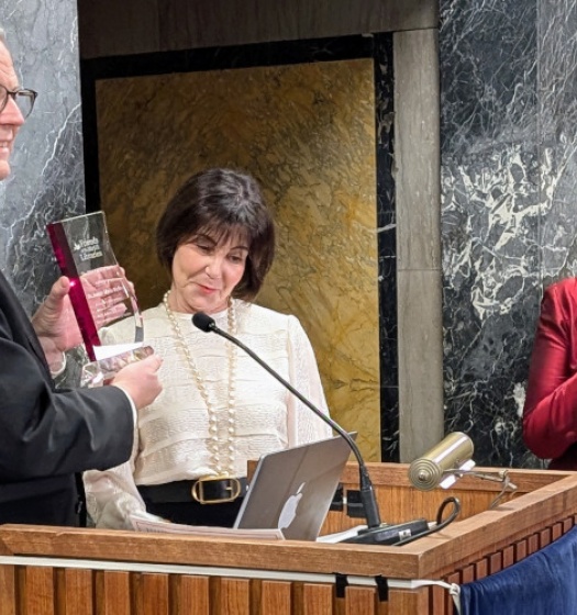 A person holding an award and standing at a podium.