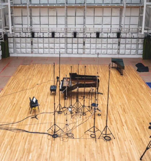 A large empty room with a piano and equipment
