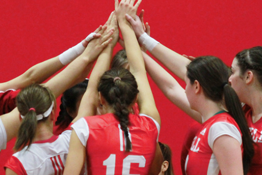 Team of girls putting hands together in a huddle