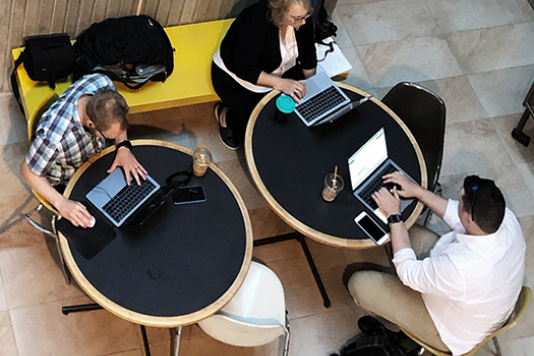 Arial view of people working on laptops at round tables